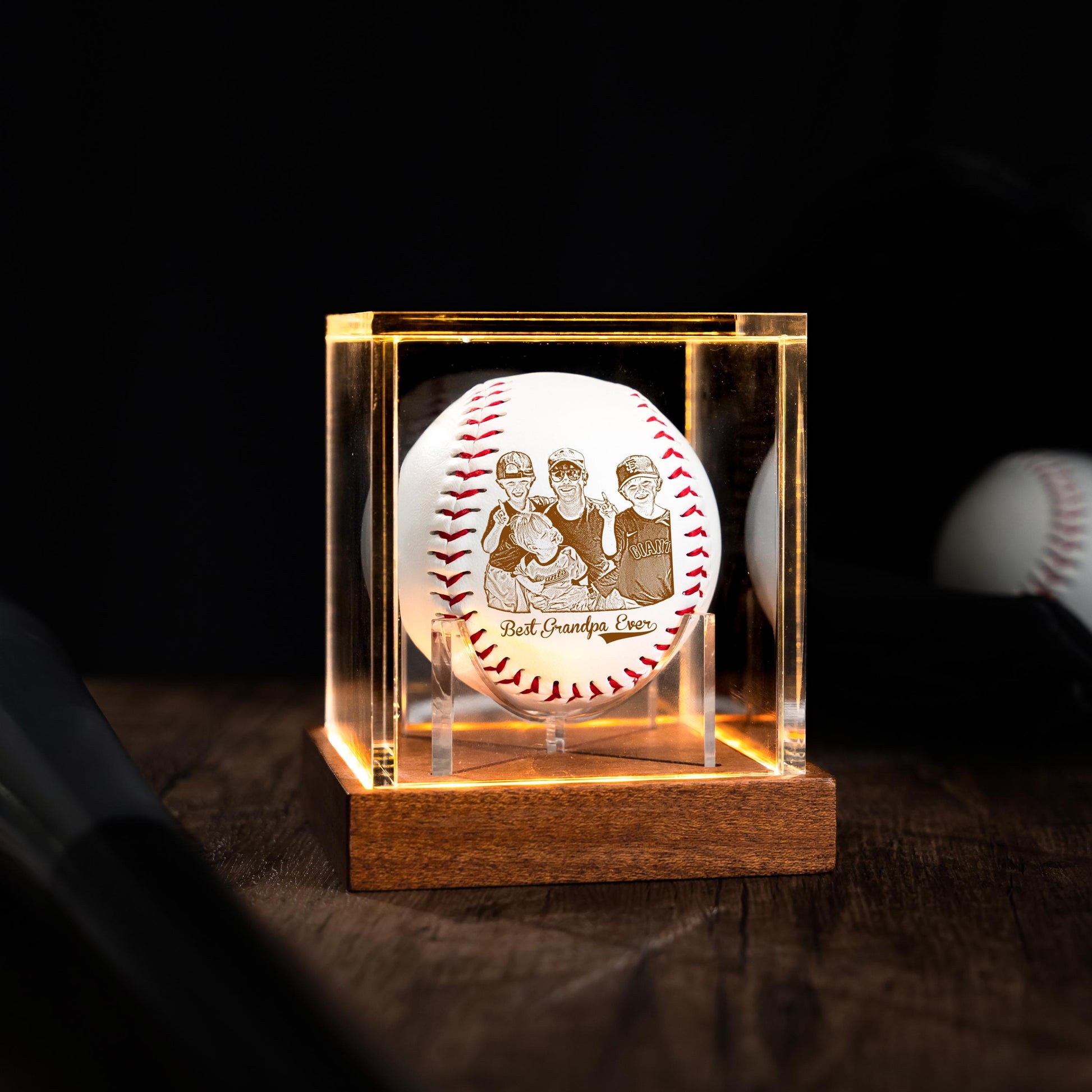 Baseball with engraved design in a clear acrylic case on a wooden base