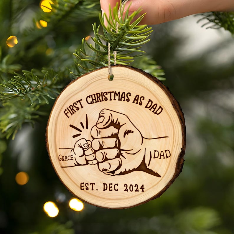 Close-up of an engraved Christmas ornament, a Personalized First Christmas As Dad Wooden Ornament, celebrating his first holiday as a father.